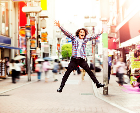 Happy young asian man jumping in Shibuya on the street, Tokyo. He is smiling and enjoy. Image is taken during Tokyo Istockalypse 2015