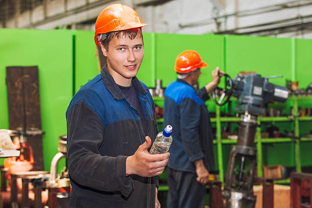 The young man working at the old factory on installation of equipment in a protective helmet