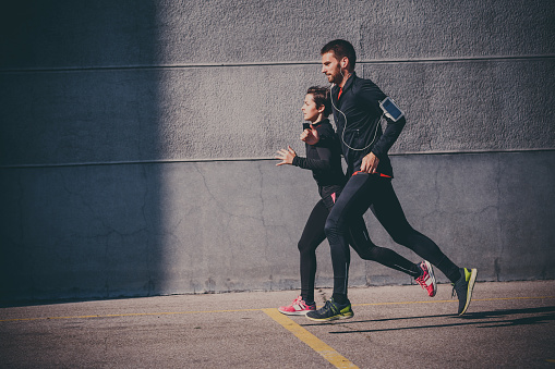 Side view of couple running in an urban environment
