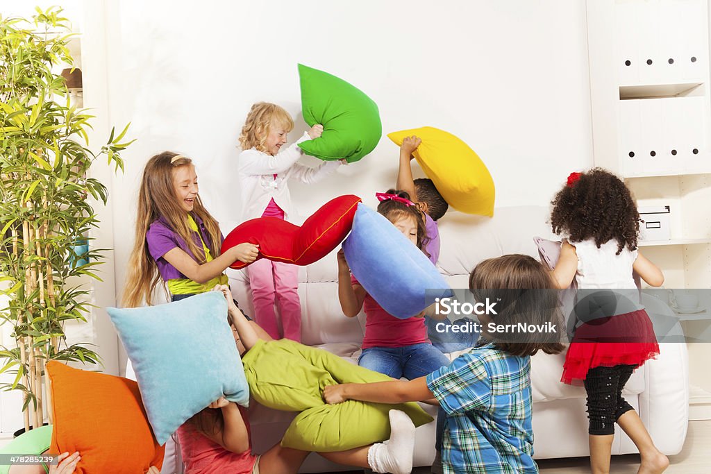 Kids playing pillow fight Pillow fight - large group of kids actively playing with pillow in the living room on the coach Pillow Fight Stock Photo