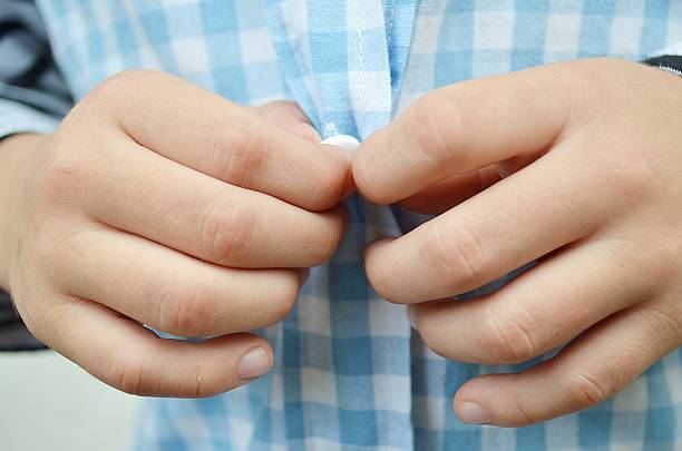 istock Little kid trying open his button shirt close up 478287299