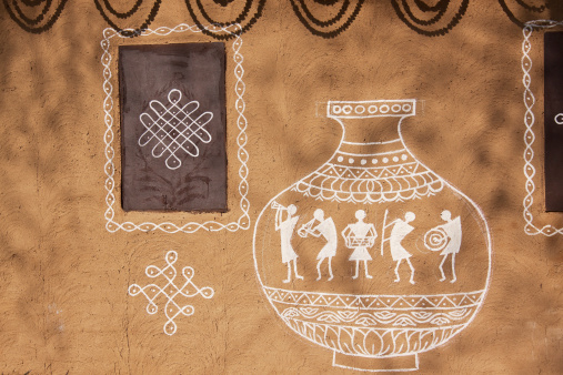 Ethnic adobe mud wall decorated with Old style village art work in white paint.