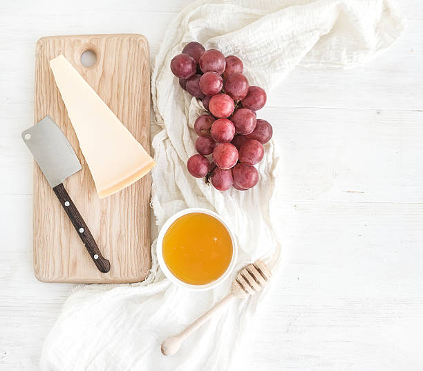 Parmesan cheese with grapes, honey and bread slices on wooden