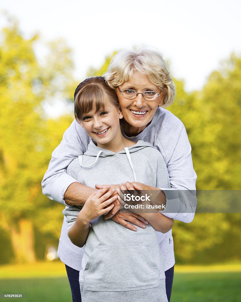 Grandma with Granddaughter, Autumn Portrait Outdoor portrait of cheerful grandmother and grandchild standing in the park, embracing and smiling at the camera. Beautiful People Stock Photo