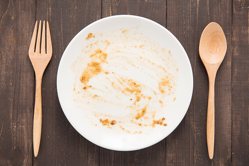 Empty dish after food on the wooden background.
