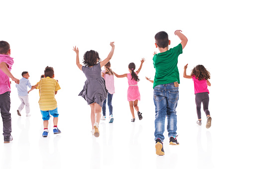 Rear view of large group of kids running with their arms raised. Isolated on white.