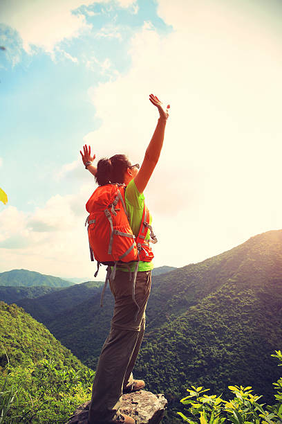 istock cheering woman hiker open arms at mountain peak cliff 478296040