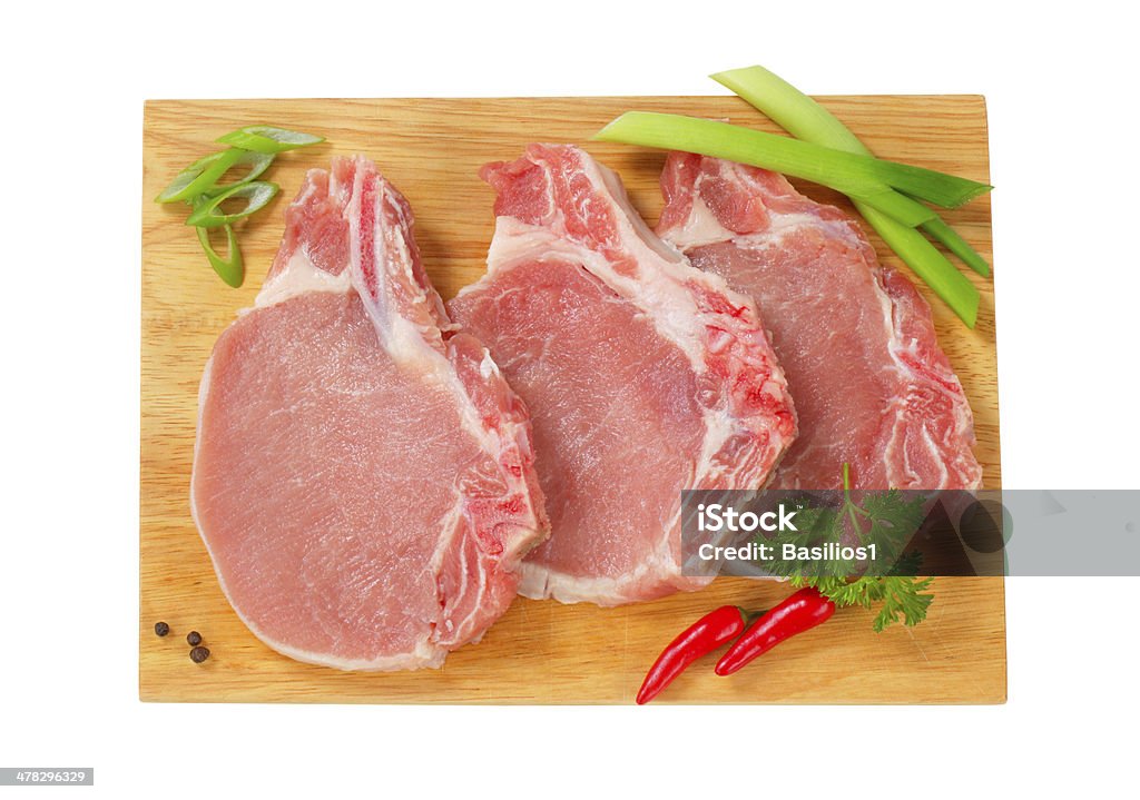 Primas chuletas de cerdo con hierbas sobre una tabla de cortar - Foto de stock de Alimento libre de derechos