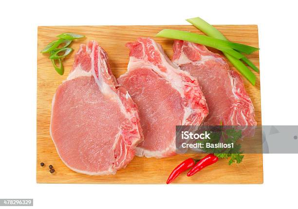 Primas Chuletas De Cerdo Con Hierbas Sobre Una Tabla De Cortar Foto de stock y más banco de imágenes de Alimento