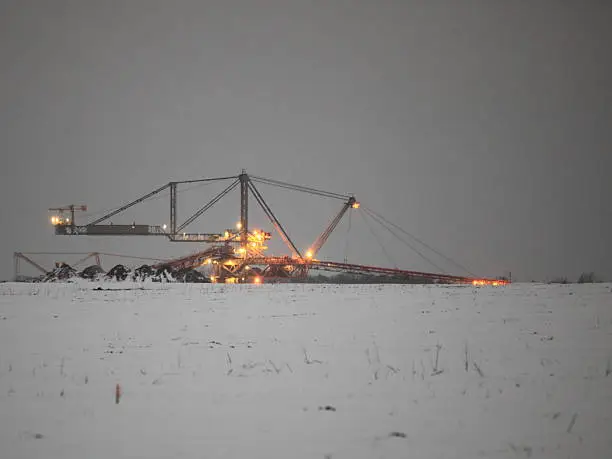 Bucket wheel excavator digging for brown coal winter night view Poland. Extractive industry