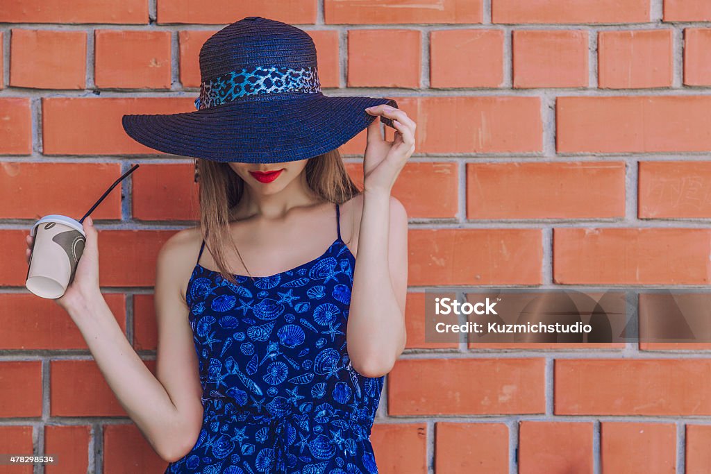 Model woman with Cup of coffee in wicker hat Model woman with Cup of coffee in wicker hat on wall background Women Stock Photo