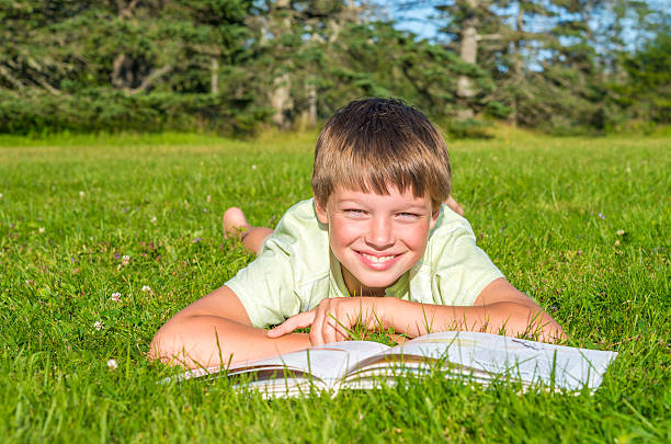 istock Boy lying on the grass with a book in park 478301101