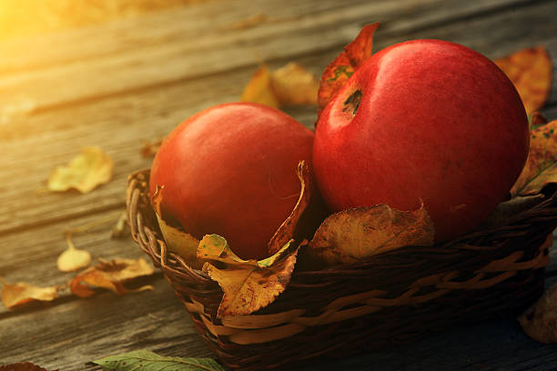 istock Apple on wooden table with fallen autumn leaves 478301897