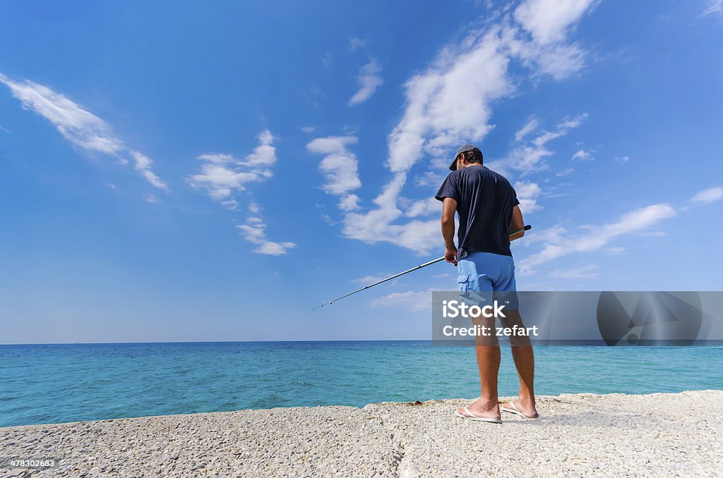 Fisherman pesca em um banco à beira-mar. - Foto de stock de Atividade royalty-free