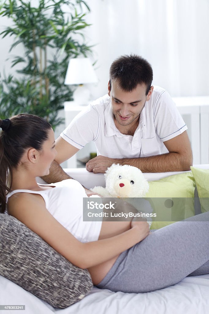 pregnant woman with her husband Portrait of a happy pregnant woman and of her husband on a sofa at home Abdomen Stock Photo