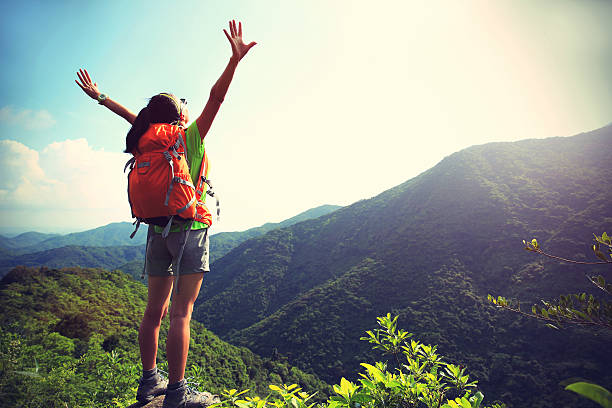 istock cheering woman hiker open arms at mountain peak cliff 478304548