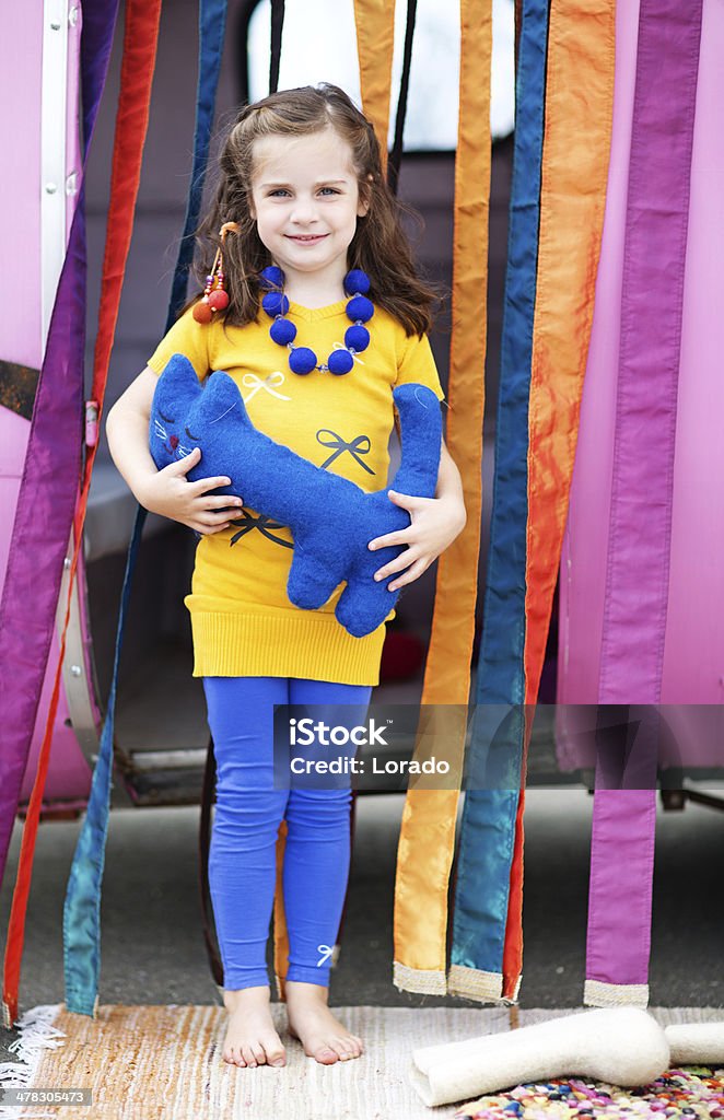 cute girl holding a toy cat posing against caravan Child Stock Photo