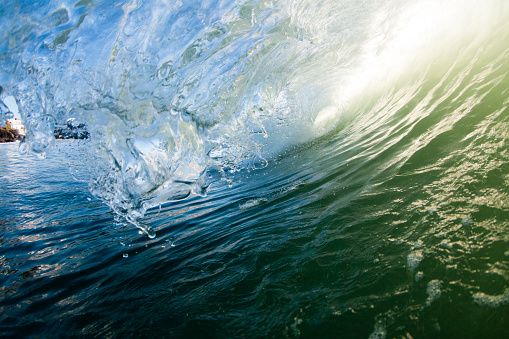 Early morning Sunlight glistens beautifully through a Cornish ocean wave. The photograph was taken from within the water and shows the curve of the wave breaking to form a shape of a tube. The picture was taken at Porthleven in south Cornwall.