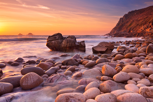 The beautiful rocky beach of Porth Nanven in Cornwall, England at sunset.