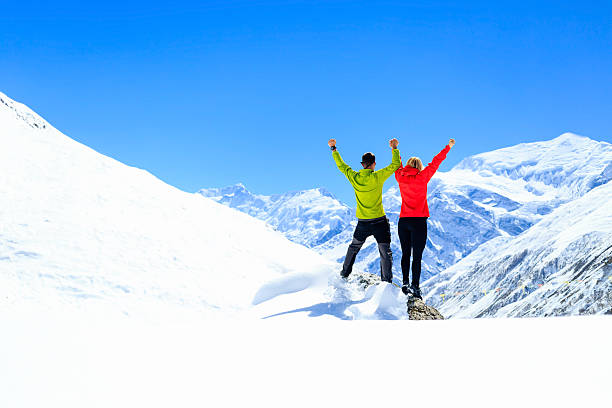 Success and achievement teamwork motivation Success and achievement, teamwork motivation, couple hikers climbers with arms up, fitness and sport woman success in winter mountains. Inspiration beautiful landscape and healthy lifestyle on snow in Himalayas, Nepal. annapurna conservation area photos stock pictures, royalty-free photos & images