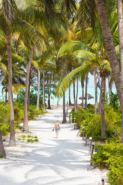 donna che cammina sulla spiaggia paje, zanzibar. - one person beautiful barefoot beach foto e immagini stock