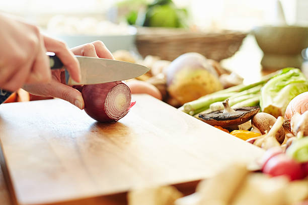 istock Cropped image of woman cutting onion at table 478312236