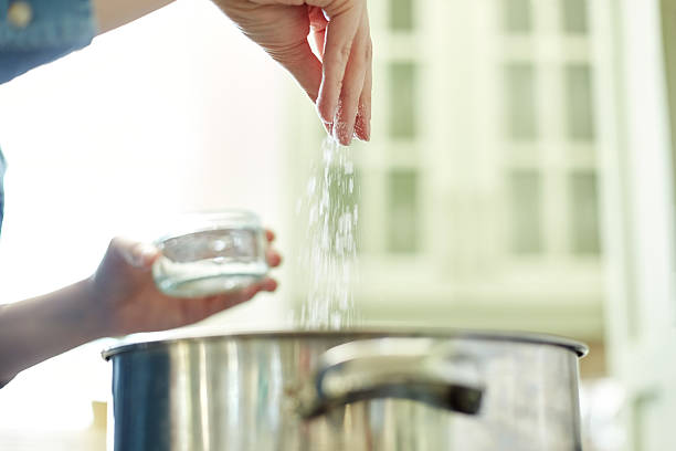 istock Below view of female hand adding salt to cooking pot 478312564