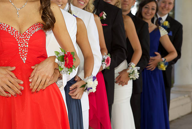 Group of Teenagers Dressed for the Prom A large group of teenagers ready for the prom standing in a line. The focus is on with their wrist corsages- most of the group is unrecognizable. prom fashion stock pictures, royalty-free photos & images