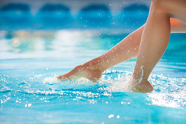 istock Woman's feet splashing the pool water 478316285