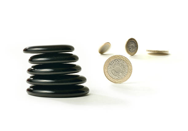 Financial Balance 3 A concept image relating to financial matters. Spinning coins representing investments, pension or savings with Feng Shui black stones representing balance. White background with copy space. golden nest egg taxes stock pictures, royalty-free photos & images