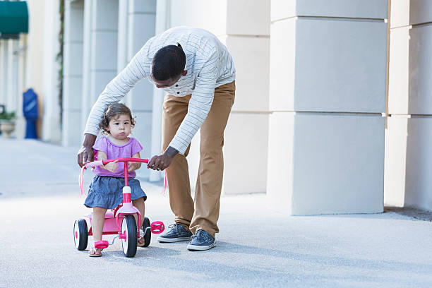 istock Father helping toddler ride tricycle 478319125