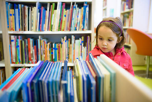 istock Little girl is choosing a book in the library 478320168