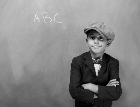Black and white portrait of little schoolboy 7-8 years old posing in front of blackboard.The text \
