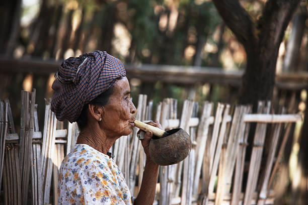 mujer fumar cigarro hechas a mano en un pequeño pueblo - bagan myanmar burmese culture family fotografías e imágenes de stock