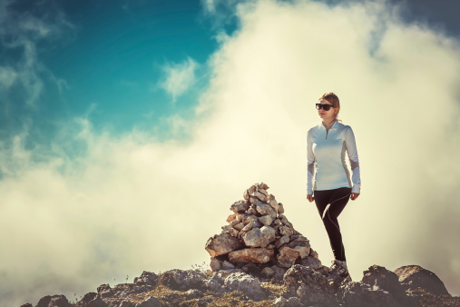 Woman Traveler on Mountain Summit with stones way sign and Clouds Sky on background Hiking Mountaineering Lifestyle summer