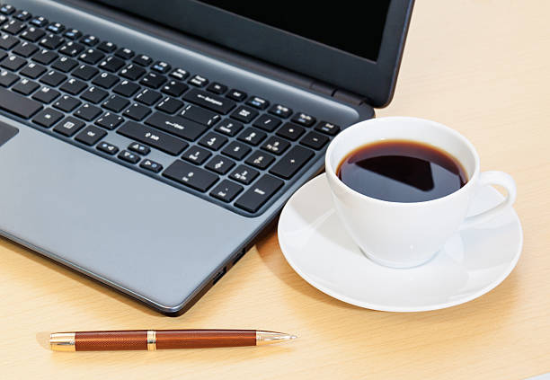 作業のオフィスデスクのコーヒーを片手に、ノートパソコン、ペン - computer key internet cafe coffee internet ストックフォトと画像