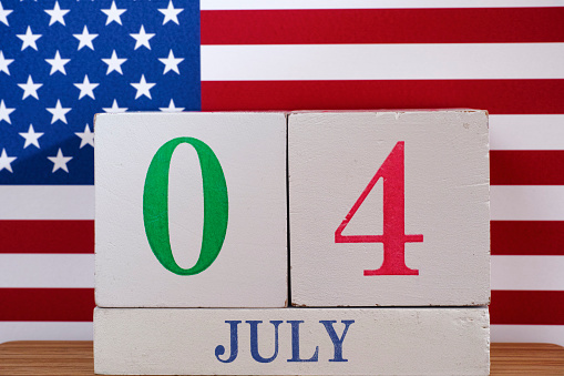 4th of July - Independence Day. Wooden calendar and American Flag.