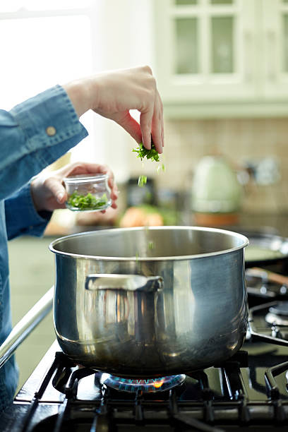 istock Female hand adding cilantro to cooking pan on stove 478329840