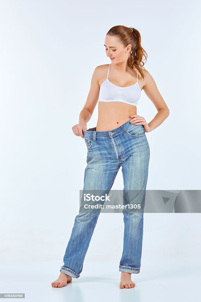 Woman became skinny and wearing old jeans Woman became skinny and wearing old jeans on white background. concept of healthy lifestyle and beauty 2015 Stock Photo