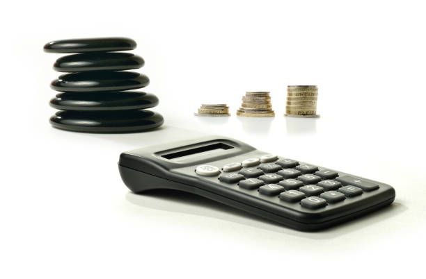 Financial Balance 5 A concept image relating to financial matters. Stacked coins representing investments, pension or savings with Feng Shui black stones representing balance and a generic calculator. White background with copy space. golden nest egg taxes stock pictures, royalty-free photos & images