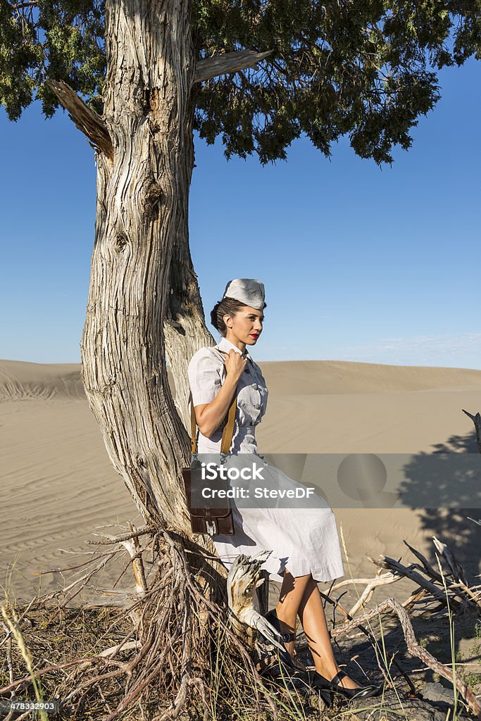 Jovem enfermeira militar descanso contra uma árvore no deserto de sol - Foto de stock de Acidentes e desastres royalty-free