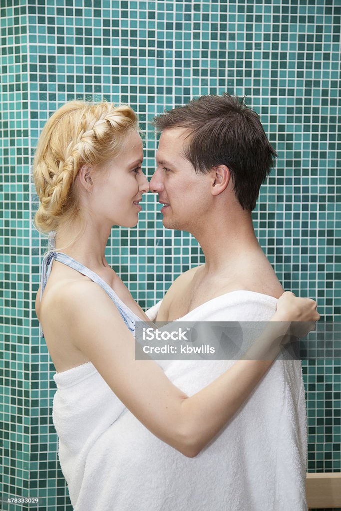 Giovane Coppia di innamorati abbraccia in un asciugamano con piscina spa - Foto stock royalty-free di Abbracciare una persona