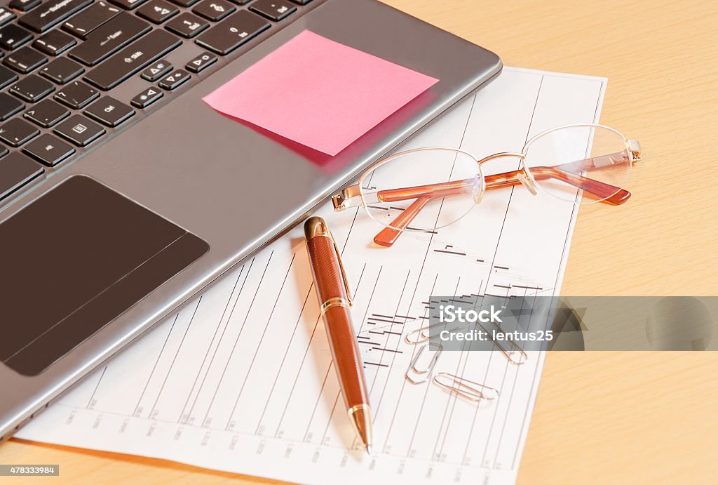 Laptop, pen and glasses on office desk. Selective focus on glasses 2015 Stock Photo