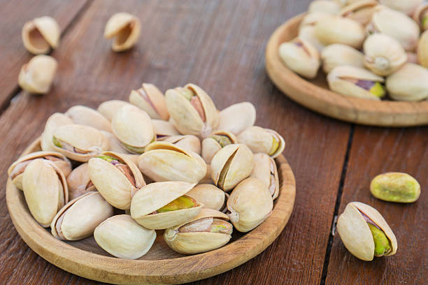 istock Roasted pistachios on wooden plate 478336393