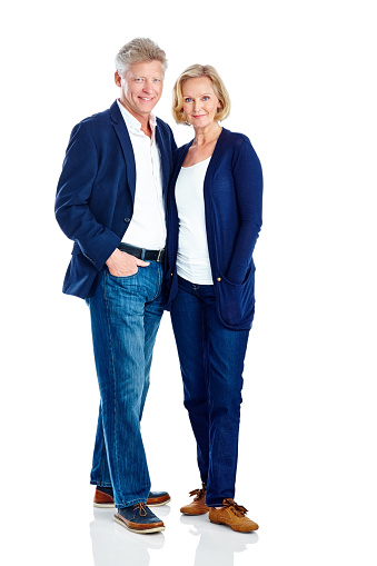 Portrait of mature couple standing together posing in casuals over white background