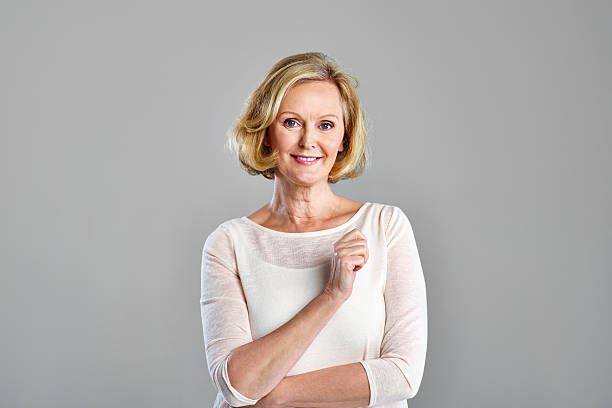 Portrait of beautiful mature woman Portrait of beautiful mature woman standing against grey background older blonde woman stock pictures, royalty-free photos & images