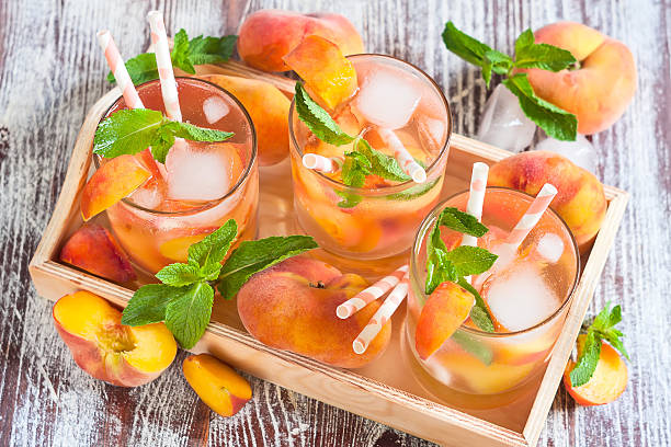 Peach lemonade Homemade lemonade with ripe flat saturn-shaped peaches and fresh mint sangria stock pictures, royalty-free photos & images