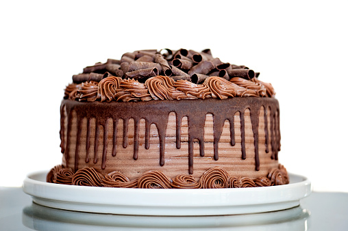 Chocolate Cake with Chocolate Fudge Drizzled Icing and Chocolate Curls on White Backdrop