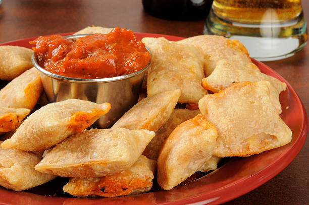 Pizza pockets and beer Closeup of a plate of pizza rolls with marinara sauce and beer in the background rolled up stock pictures, royalty-free photos & images