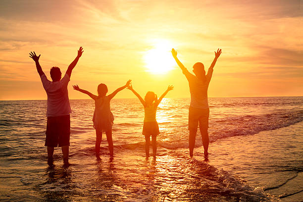 istock happy family watching the sunset on the beach 478354624